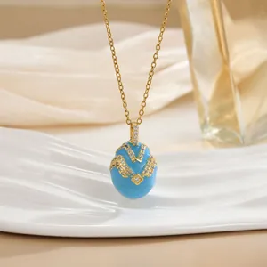 Macro detail of sky blue enamel egg pendant with gold wave patterns and zircon stones
