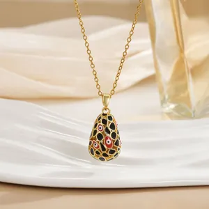 Detail of 18K gold plated teardrop pendant with enamel evil eye and hollow geometric pattern