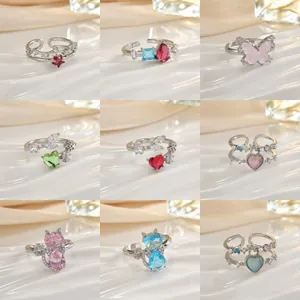 Nove diversi anelli regolabili in argento con zirconi luccicanti e motivi floreali colorati