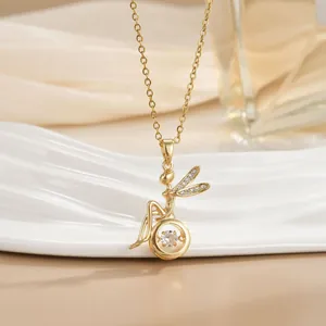 Close-up of golden fairy pendant with sparkling zircon wings and dancing center stone
