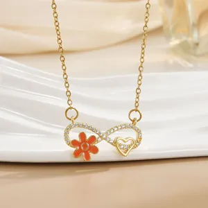 Detailansicht der goldenen Infinity-Halskette mit orangen Blumen und Herz-Anhänger