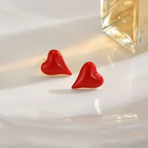 Close-up of red heart earrings with high-gloss enamel finish on a white ceramic plate