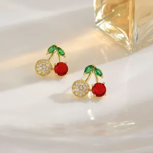 Detailed close-up of cherry earrings with red stones and sparkling diamond leaves