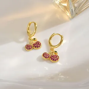 Detail view of gold cherry earrings with sparkling red and green cubic zirconia crystals