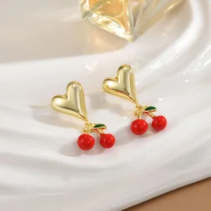 Elegant 18K gold plated heart and red cherry drop earrings on a white textured tray