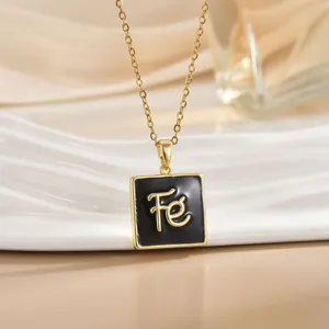 Macro view of gold stainless steel necklace with black enamel square FE letter pendant