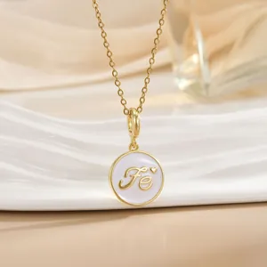 Macro shot of gold necklace featuring white enamel round pendant with Fe letters and heart