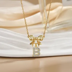 Elegant gold bow necklace with letter B pendant and zircon crystals on champagne satin