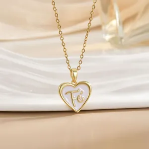 Macro shot of gold heart pendant with white enamel and Fé engraving on a gold chain