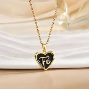 Macro detail of heart-shaped black enamel Fé pendant with golden chain on white ceramic plate