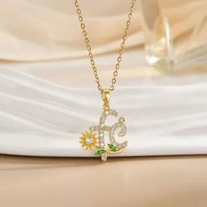 Macro shot of gold necklace featuring letter F pendant with sunflower and zircon stones