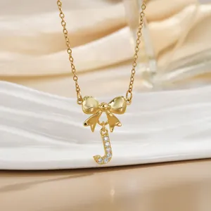 Macro detail of golden bow necklace featuring a sparkling letter J pendant with zircons