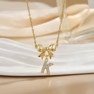 Macro shot of gold bow necklace with letter K pendant inlaid with sparkling zircon crystals