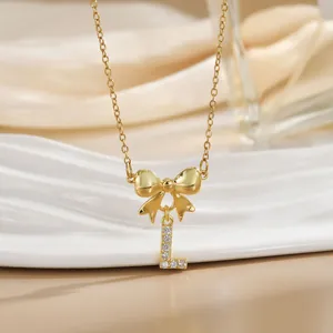 Detailed close-up of bow knot necklace with zircon letter L pendant in gold