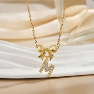 Detailed macro of gold bow necklace with micro-pave zircon letter M pendant charm