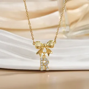 Macro shot of gold bow necklace with letter R pendant inlaid with zircon crystals