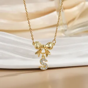 Macro shot of gold bow pendant with zircon-encrusted letter S on a steel necklace