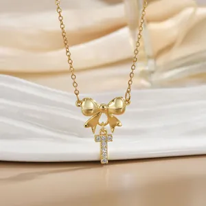 Macro detail of golden bow necklace featuring a sparkling zircon-encrusted letter T pendant