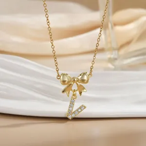 Macro shot of gold bow necklace with letter L pendant and cubic zirconia details