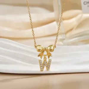 Close-up of golden bow and zircon inlaid letter W pendant necklace on velvet display
