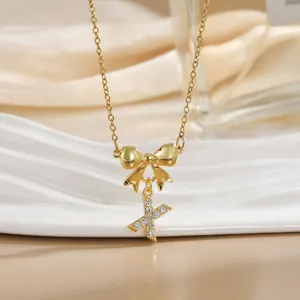 Macro shot of gold bow necklace with sparkling zircon Letter X pendant for women