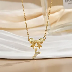 Close-up of gold bow necklace with zircon letter Y pendant on champagne silk fabric