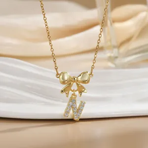 Detail of gold bow necklace with letter N pendant featuring micro-paved sparkling crystals