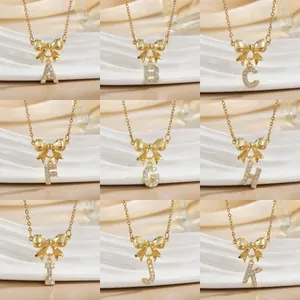Gold bow necklace collection with zircon-inlaid alphabet charms on wavy display stands