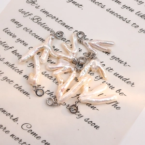 Ciondolo in perla d'acqua dolce barocca con chiusura in argento su sfondo di carta vintage