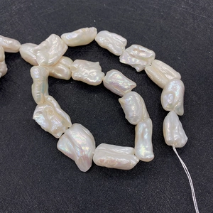 Vue macro de perles d'eau douce baroques blanches avec éclat irisé sur fond noir