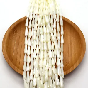 Natural teardrop shell loose beads in pearly white on a wooden tray for jewelry making