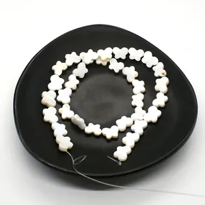 Natural white mother of pearl butterfly beads for DIY jewelry making on black plate