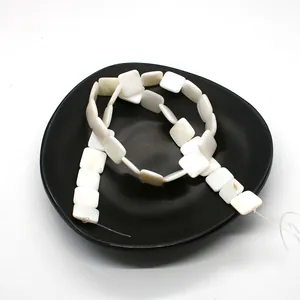 Macro shot of square white mother of pearl loose beads for DIY jewelry making in a black tray