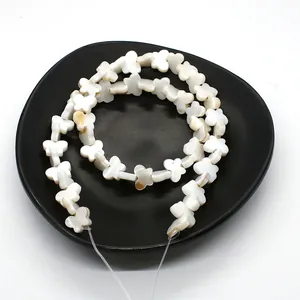 Macro shot of butterfly-shaped natural shell beads in a black tray for DIY jewelry