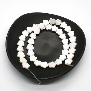 Macro detail of white flower-shaped natural shell beads with pearlescent luster for DIY jewelry
