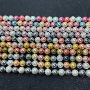 Primo piano di perle finte tonde colorate disposte in file su una superficie nera testurizzata