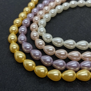 Makroansicht von tropfenförmigen Perlen in Gold, Lila und Rosa für DIY-Schmuck