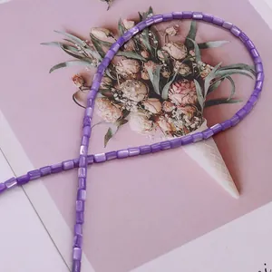 Vista macro di perle cilindriche viola in conchiglia con finitura perlata per gioielli