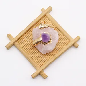 Macro detail of raw purple amethyst crystal pendant with gold plated textured edges