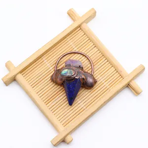 Detailweergave van een pijlpunthanger met amethist en abalone schelp op bamboe standaard