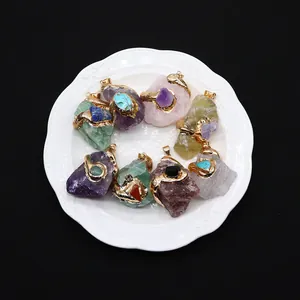 Natural crystal stone pendants with gold plated snake wire wrap on a white ceramic plate