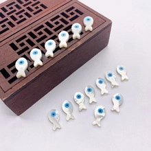 Detailed macro view of small fish-shaped natural shell beads with blue evil eye accents