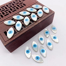 Macro detail of marquise evil eye shell beads for jewelry making on wooden background