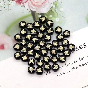 Macro detail of black natural shell beads with gold butterfly print for DIY jewelry making