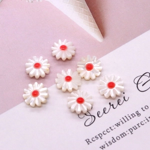 Detailed view of white daisy flower beads with red centers for DIY jewelry making
