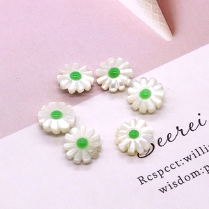 Macro detail of six white daisy shell beads with green centers for jewelry making