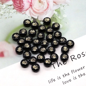 Detailed macro view of black shell beads with golden rose patterns for DIY jewelry making