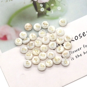 Close-up of round shell beads with gold ampersand symbol for DIY necklace jewelry