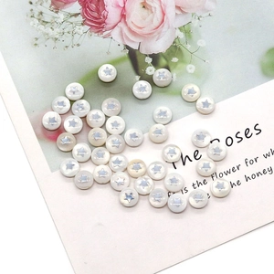 Macro detail of round white pearl shell beads with silver star pattern for DIY jewelry making