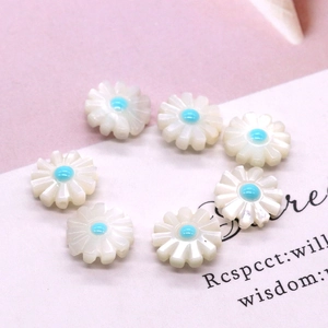 Macro detail of daisy-shaped natural white shell beads with light blue centers for DIY jewelry